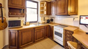 A kitchen with wooden cabinets, a window, a stove, a sink, and a microwave. - Harrachov 561 by Interhome (Harrachov)
