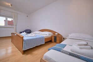 Une chambre à coucher avec un lit en bois, une chaise, une table de chevet et une fenêtre avec des rideaux.