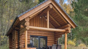 A log cabin with a porch, outdoor seating, and a large window. - Vacation home KuŘíp by Interhome (Benesov nad Cernou)