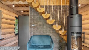 A log cabin interior with a blue chair, a wood-burning stove, and a stone wall. - Vacation home KuŘíp by Interhome (Benesov nad Cernou)