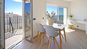 En moderne lejlighed med balkon, spiseplads med bord og stole, samt udsigt over byen og havet.