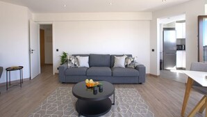 En moderne stue med en grå sofa, et rundt sofabord og et gulvtæppe med geometrisk mønster.