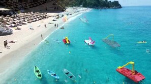 Uma praia com águas turquesa cristalinas, vários caiaques e algumas pessoas.
