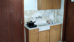Una cocina compacta con muebles de madera, un protector antibarrotes de mármol y una encimera con estufa eléctrica negra.