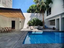 Una piscina al aire libre, sillones reclinables de piscina