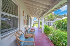 Relax in a serene outdoor space with comfortable wicker chairs and lush green surroundings.