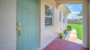 A house with a teal door, a small porch, and a pathway leading to a grassy yard. - Charming 2BR Dania Beach Bungalow Getaway (Dania Beach)