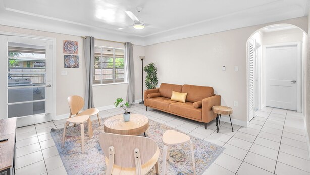A living room with a beige sofa, two wooden chairs, a small round table, and a potted plant. - Charming 2BR Dania Beach Bungalow Getaway (Dania Beach)