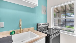 A kitchen with a sink, stove, and window with blinds. - Charming 2BR Dania Beach Bungalow Getaway (Dania Beach)