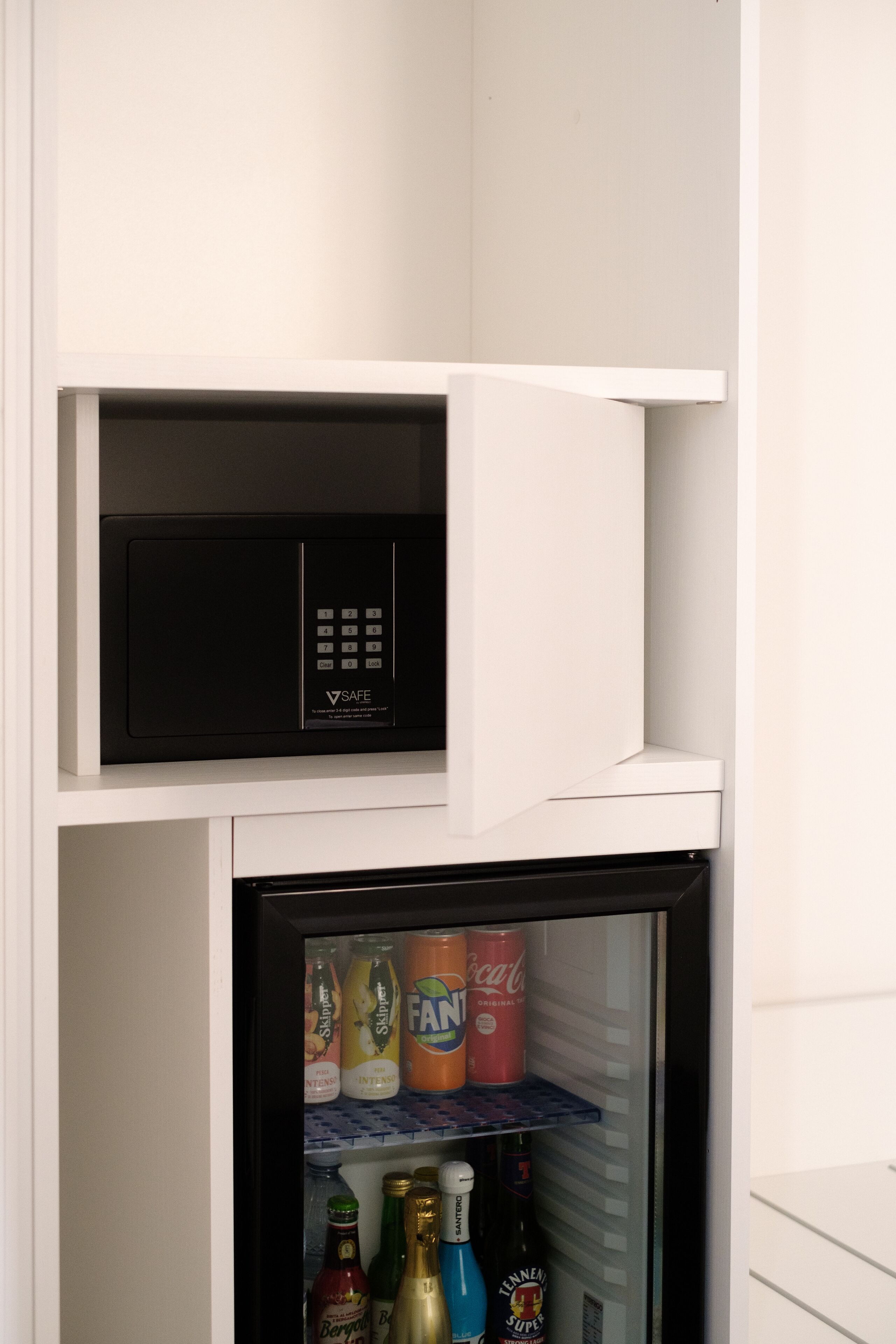 A compact refrigerator with a freezer compartment, containing various beverages and bottles.