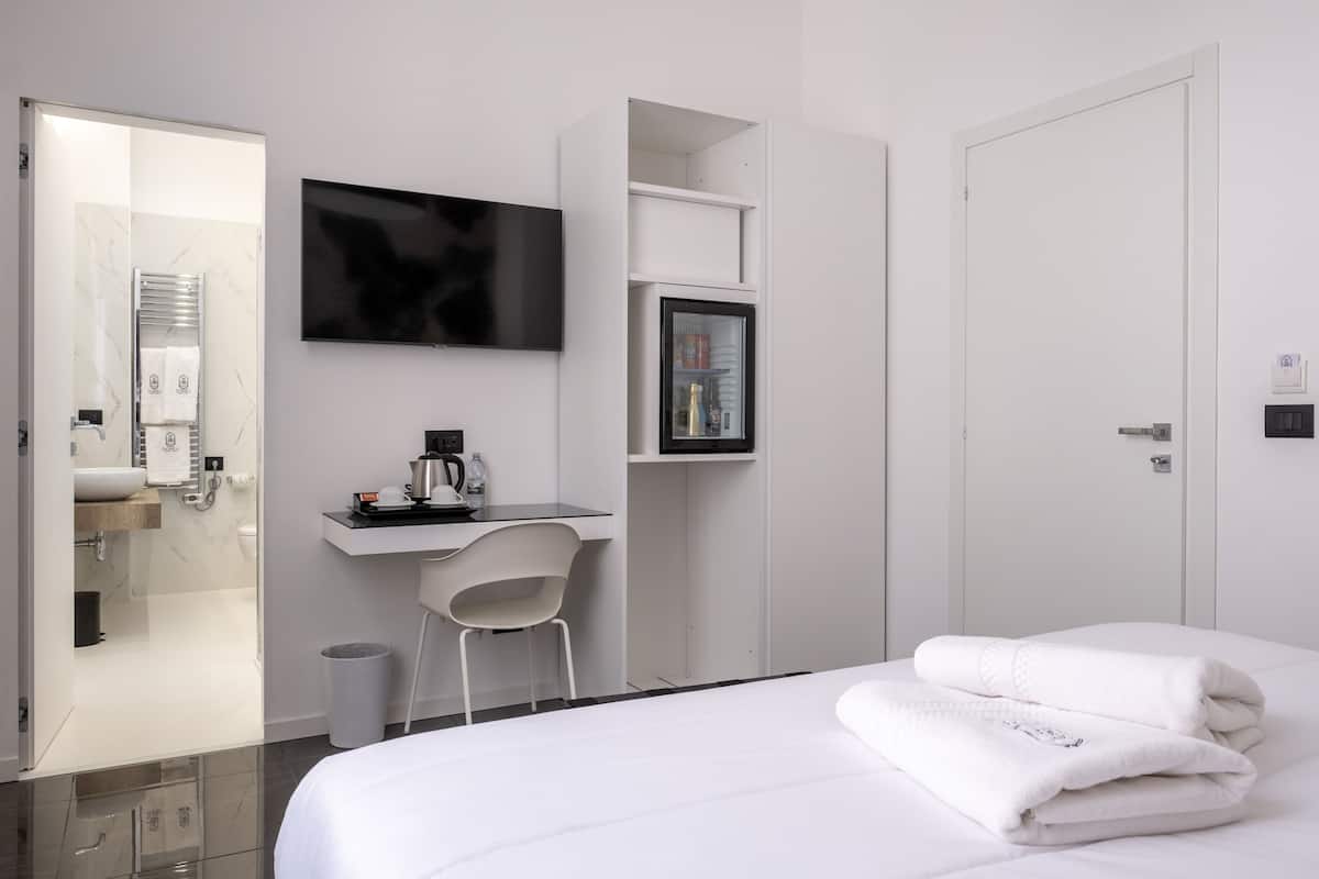 Une chambre d’hôtel moderne équipée d’un lit, d’un bureau, d’une chaise, d’une télévision et d’une porte.