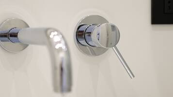 A modern bathroom with a white sink and two chrome faucets.