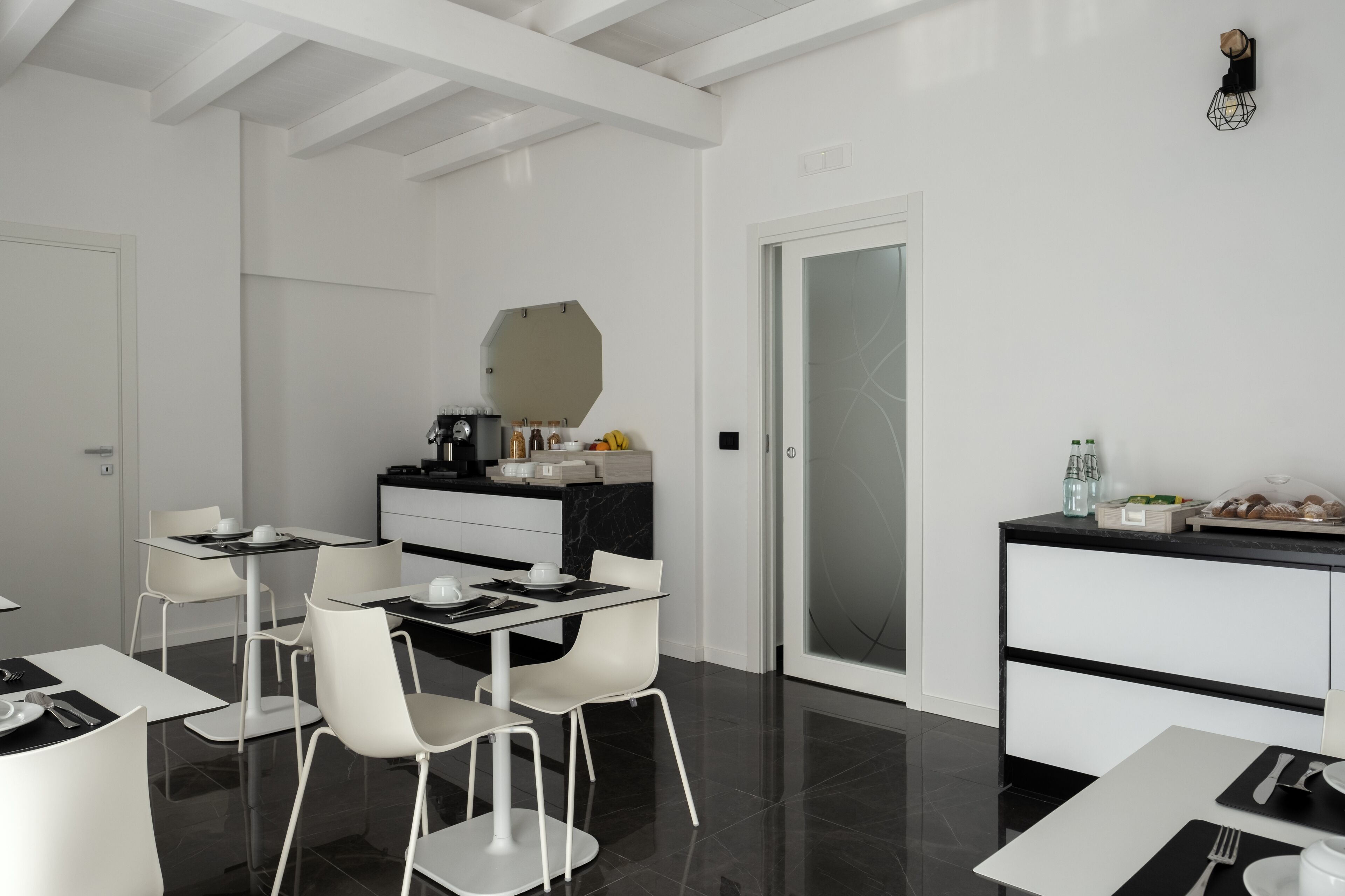 A modern, minimalist dining area with white furniture and a sleek black countertop.