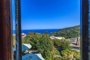 Une vue sur la côte, depuis une fenêtre donnant sur une colline, avec un ciel bleu dégagé.