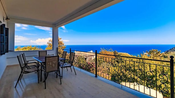 A balcony with a view of the sea, a table with chairs, and a decorative railing. - Apartment Zina Pelion (Zagora-Mouresi)