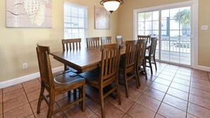 Un coin repas avec une table et des chaises en bois, un lustre et une vue à travers une porte vitrée.