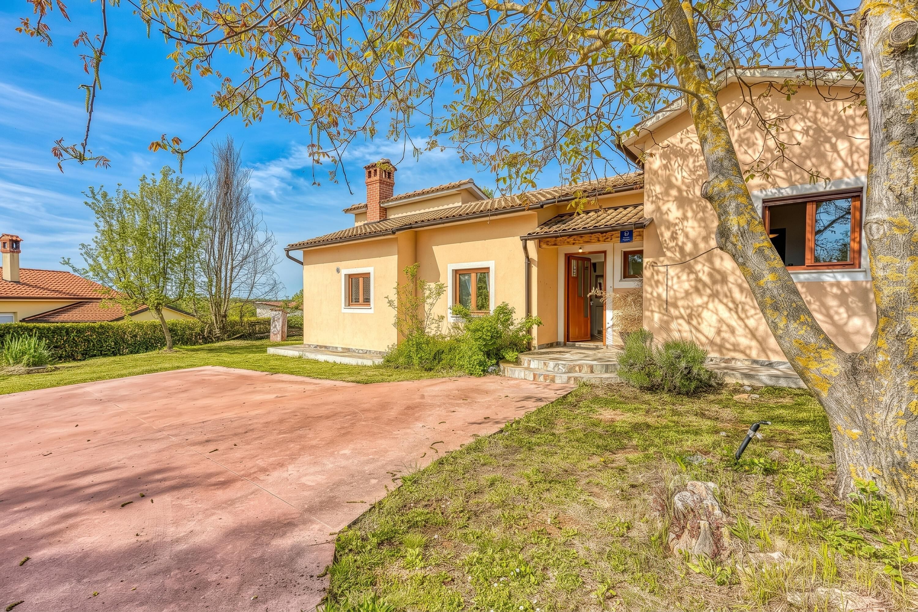 A two-story house with a red-tiled roof, a front porch, and a paved driveway.