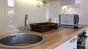 Une cuisine équipée d’un évier en acier inoxydable, d’un plan de travail en bois et d’un four à micro-ondes.