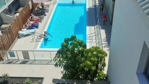 Una piscina en la azotea con tumbonas y sombrillas, rodeada de edificios.