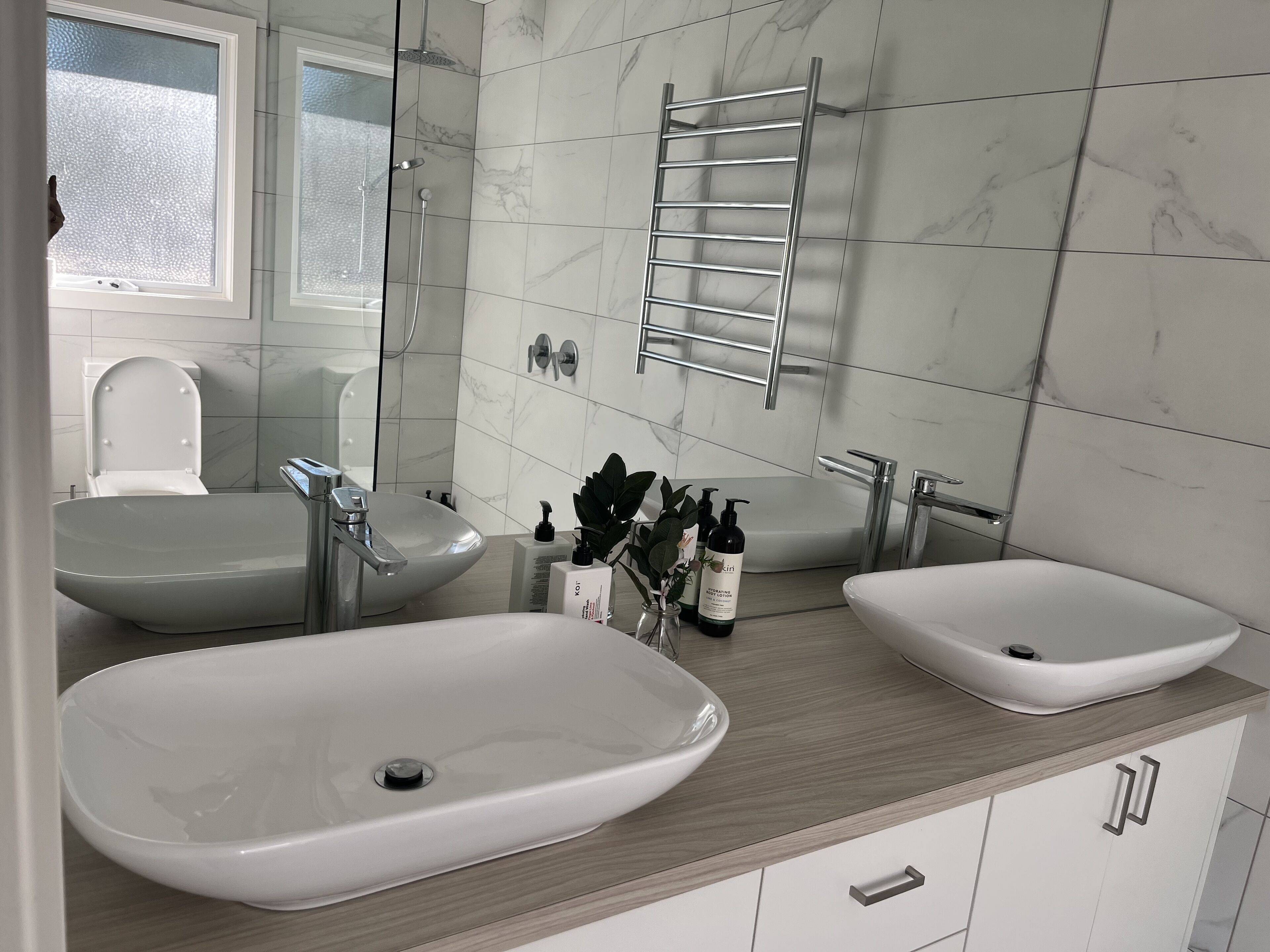 Un baño moderno con dos lavamanos, ducha y un perchero para toallas.