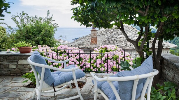 Two rocking chairs facing a stone wall with pink flowers and a view of the sea. - Villa Zina Studio 3 Pelion (Zagora-Mouresi)