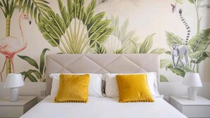A bedroom with a large bed, white bedding, and two yellow pillows. There is a mural on the wall depicting a flamingo, palm trees, and a lemur. - Accogliente appartamento con piscina privata.
TROPICAL LOFT (Salemi)