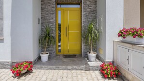 A yellow door with a stone facade, potted plants, and a white cabinet. - Accogliente appartamento con piscina privata.
TROPICAL LOFT (Salemi)