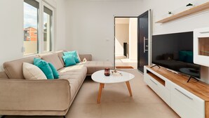 A modern living room with a beige sofa, a round coffee table, and a flat-screen TV on a wooden stand. - Modern Villa AdriaStar with a swimming pool (Dugi Rat)