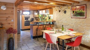 A dining area with a stone wall, a painting, and a wooden ceiling. - Gîte Classé 3 Avec Sauna Chez Chanchan 4/ 6 Pers (Dambach-la-ville)