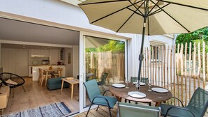 An open-plan living area with a dining table, chairs, and a large umbrella.