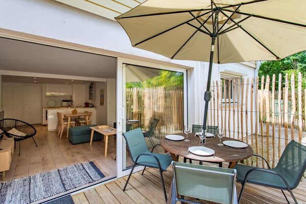 An open-plan living area with a dining table, chairs, and a large umbrella.
