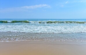 Una playa con olas acercándose a la orilla bajo un cielo despejado.
