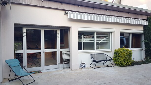A modern house with large windows, a covered patio, and outdoor furniture. - Maisonnette (Chambéry)