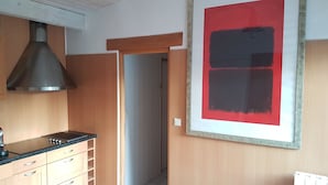 A kitchen with wooden cabinets, a black countertop, and a stainless steel range hood. - Maisonnette (Chambéry)