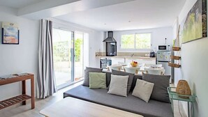 A modern living room with a sofa, a dining table, and a kitchen in the background.