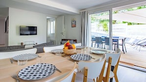 A dining area with a table set for four, a fruit bowl, and a television on the wall.
