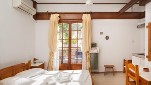 A bedroom with a wooden bed, a desk, a chair, a radiator, and a window with curtains.