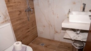 A bathroom with a wooden floor, a white sink, and a shower.