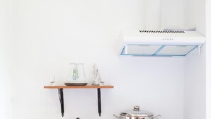 A compact kitchen with a sink, a small countertop, a pot on a portable stove, and a shelf with glassware. - Paradeisos Double Room With Sea View 4 (Zagora-Mouresi)