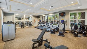Une salle de sport équipée de tapis de course, de vélos elliptiques et de matériel de musculation.