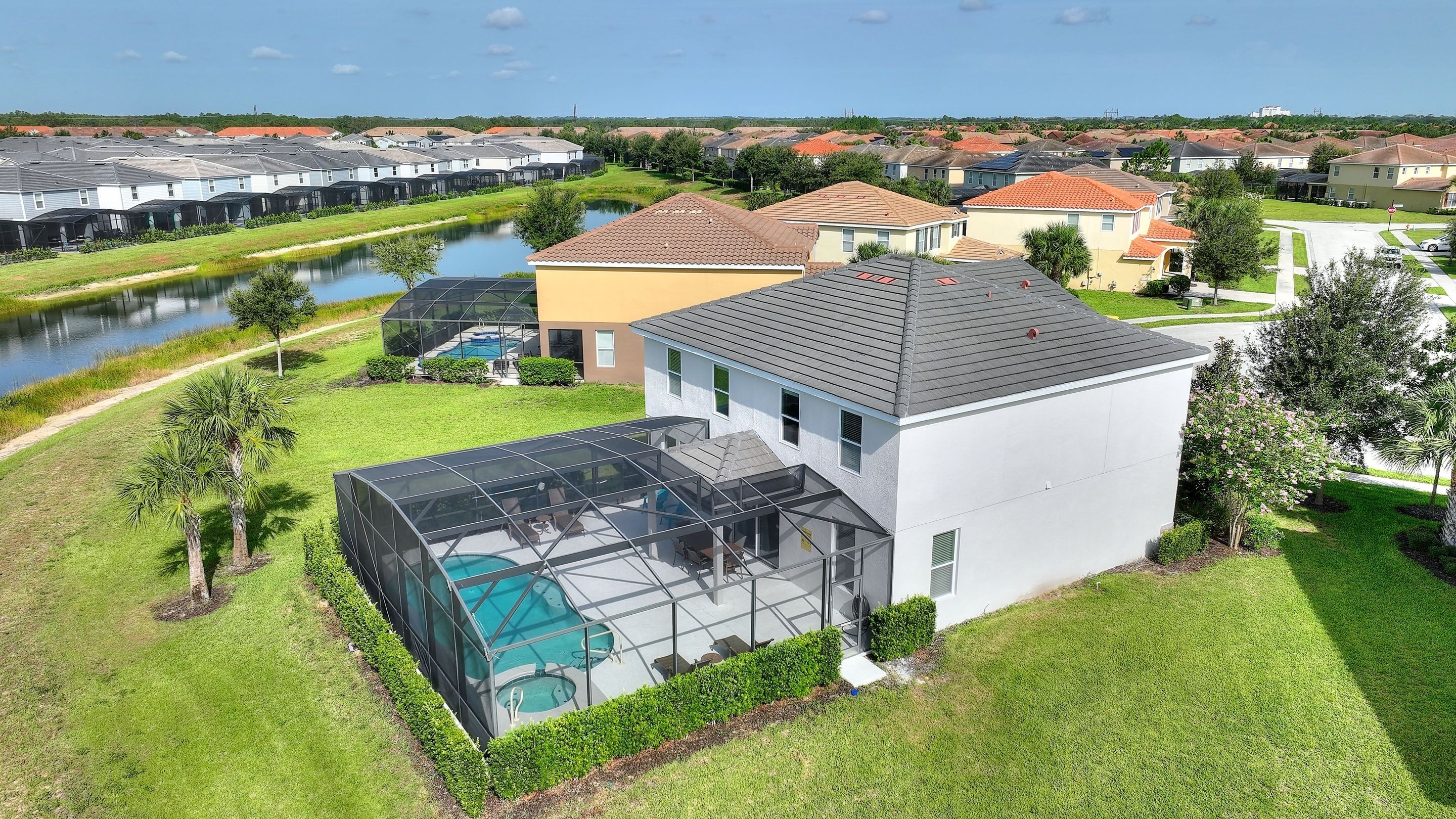 Une maison moderne dotée d’un grand espace piscine entièrement vitré, d’une pelouse bien entretenue et d’une vue sur une rivière.