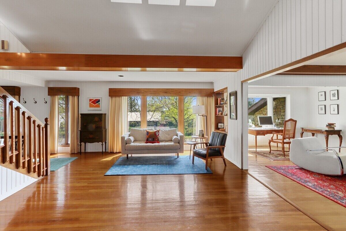 A spacious living area with a wooden floor, a sofa, a coffee table, and a fireplace.
