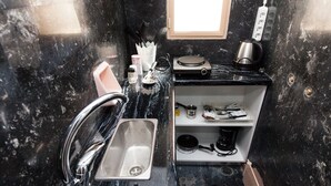 A kitchen with a stainless steel sink, a kettle, and a microwave on a black countertop. - Brand new 1 Bedroom Apt in Kolonaki (Athens)