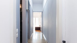 A hallway with a light-colored floor, a bench, and a door at the end. - Brand new 1 Bedroom Apt in Kolonaki (Athens)