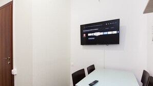 A conference room with a flat-screen TV mounted on the wall displaying a streaming service interface. - Brand new 1 Bedroom Apt in Kolonaki (Athens)