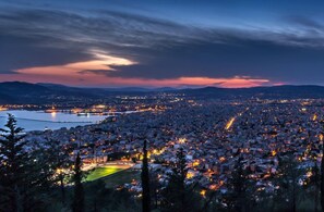 A panoramic view of a city at dusk with a stadium in the foreground and a river in the background.
