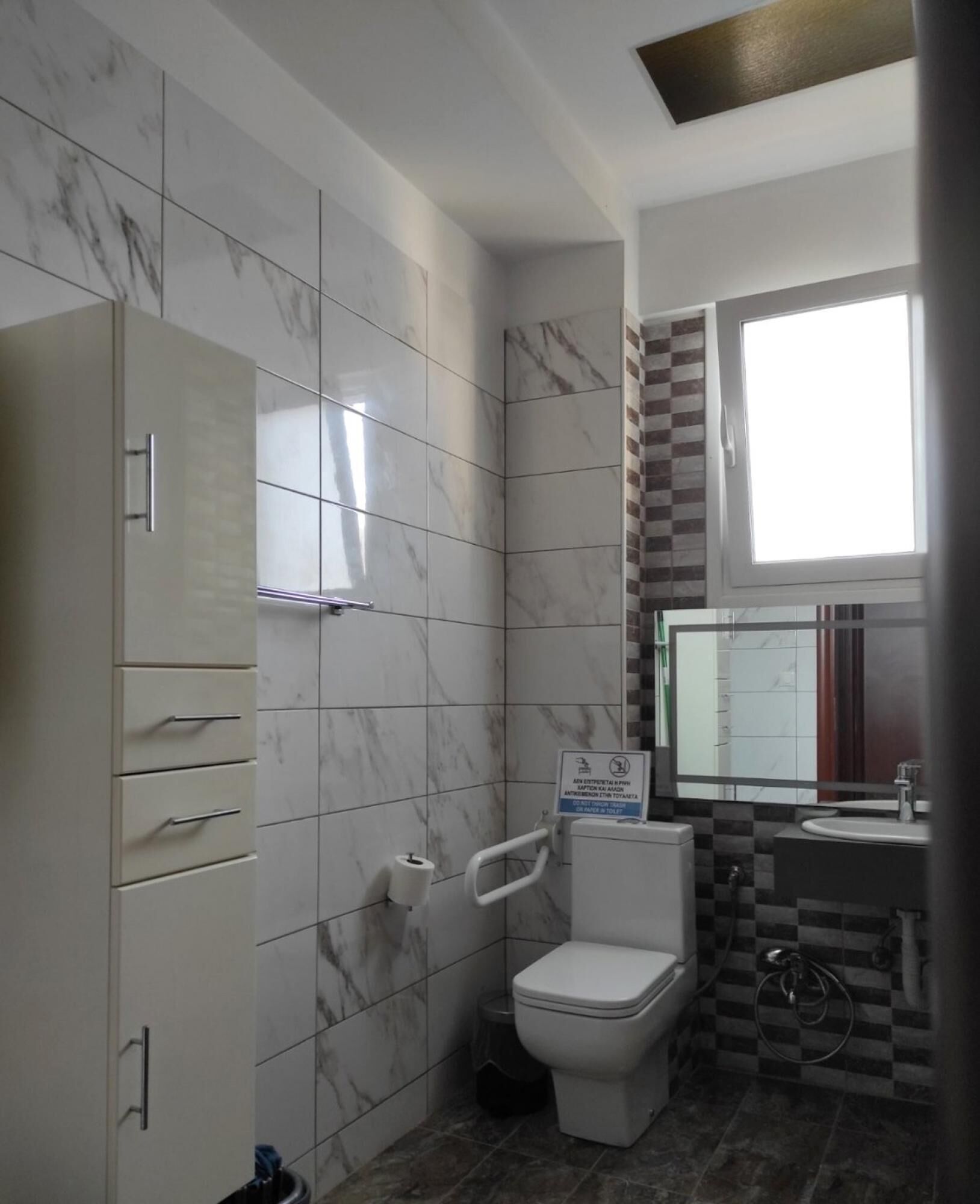 A bathroom with a toilet, sink, and cabinet.