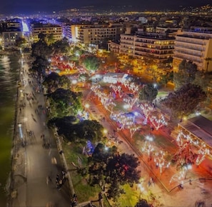 A nighttime view of a riverside promenade with buildings and trees.