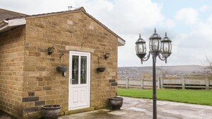A stone building with a white door, two hanging baskets, and a street lamp.