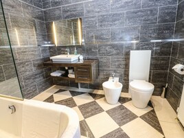 Un baño moderno con un espejo grande, un lavabo, un inodoro y una bañera.